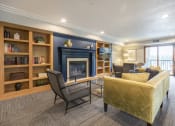 Thumbnail 9 of 27 - Community room with a variety of seating in front of a fireplace, pillared by bookshelves
