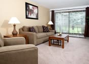 Thumbnail 4 of 19 - Living room with couch, chair, coffee table, and a view of a patio