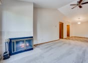 Thumbnail 4 of 26 - Empty living room with a corner fireplace, white carpets, and a ceiling fan