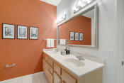 Thumbnail 14 of 40 - Bathroom with twin sinks and an orange wall with artwork