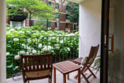 Thumbnail 8 of 23 - Outdoor patio with wooden chairs facing tall fauna