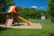 Thumbnail 24 of 27 - children's outdoor playground with swings, climbing wall, slide, and rainbow canopy, on a sunny day