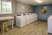 Thumbnail 14 of 17 - Laundry room with many washing machines and dryers and a folding table