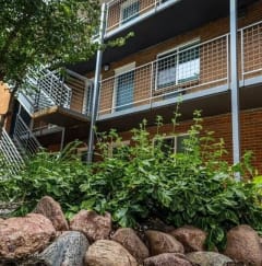 an apartment building with a rock garden in front of it