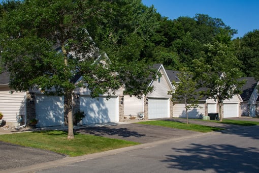 row of houses with garages and two large trees out front