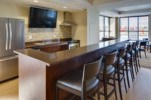 community kitchen with stool seating facing a large TV mounted on the wall
