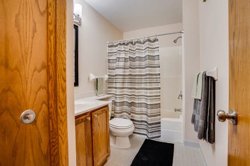 Bathroom with wooden cabnets and striped shower curtain