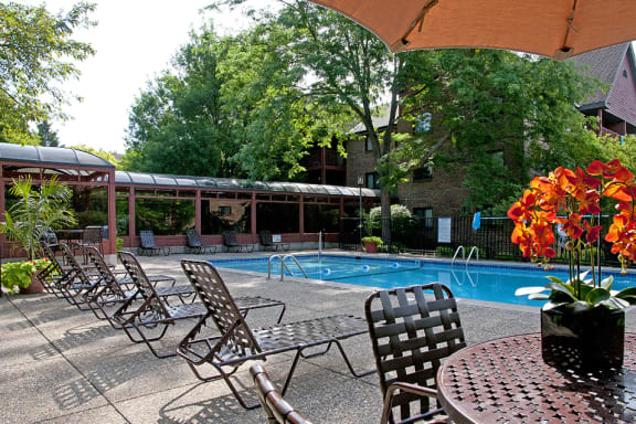 Outdoor pool with lounge chairs, umbrella tables, and shaded areas