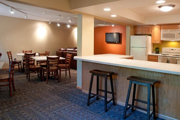 Community room with kitchen, bar seating, and square tables