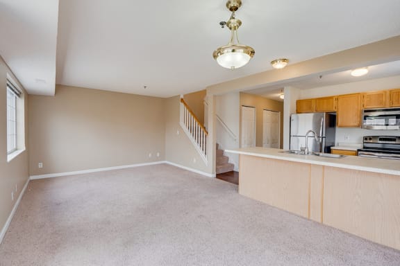 carpeted living room with view of the stairs and kitchen