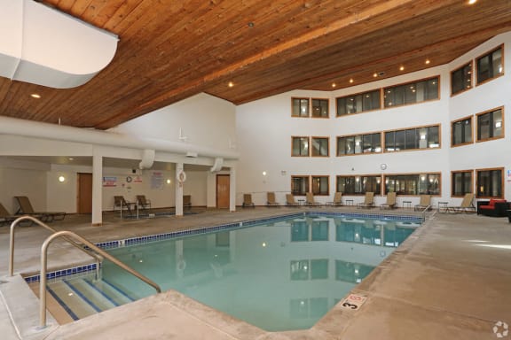 Indoor pool with high ceiling and lounge seating