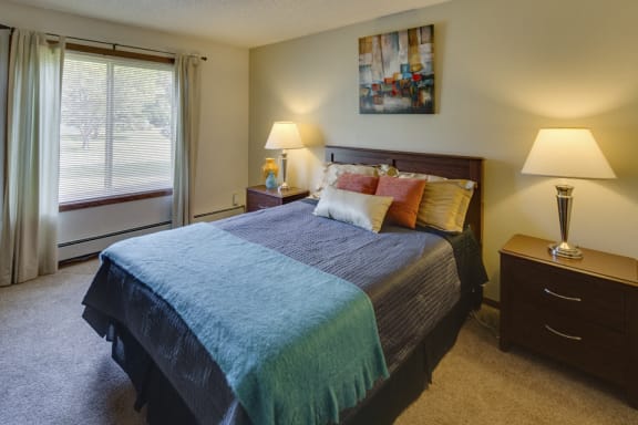 Bedroom, wall art, green and purple bedspread, and lamps