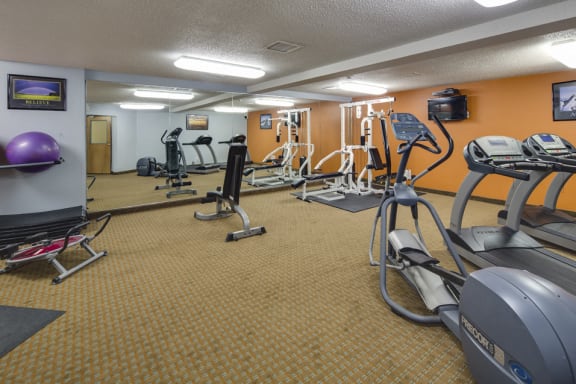 Fitness room with various equipment and a large mirror wall