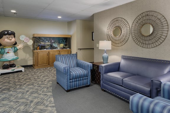 Lobby with a blue sofa and chairs, a fishtank, and a Peanuts "Lucy" statue