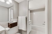 Thumbnail 7 of 23 - White bathroom with bright lights and the camera facing the bathtub and shower