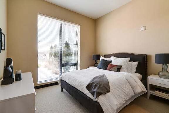 Bedroom with queen sized bed, nightstands with lamps, and a dresser