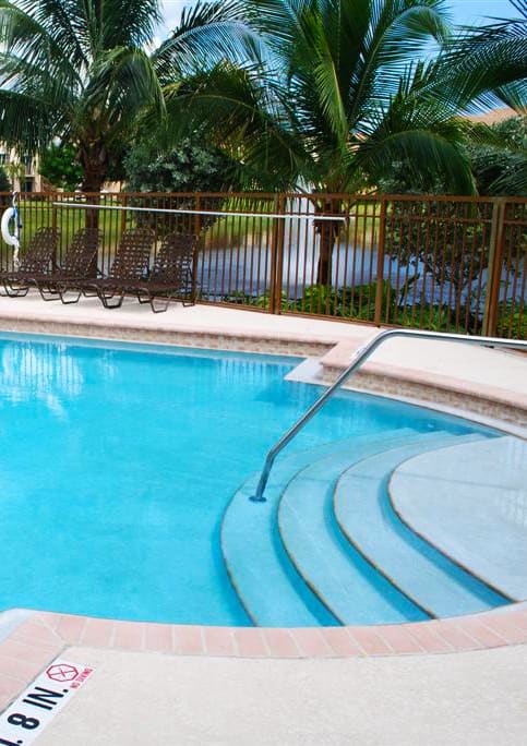 a large blue swimming pool with palm trees in the background at Sanctuary Cove, North Lauderdale, 33068