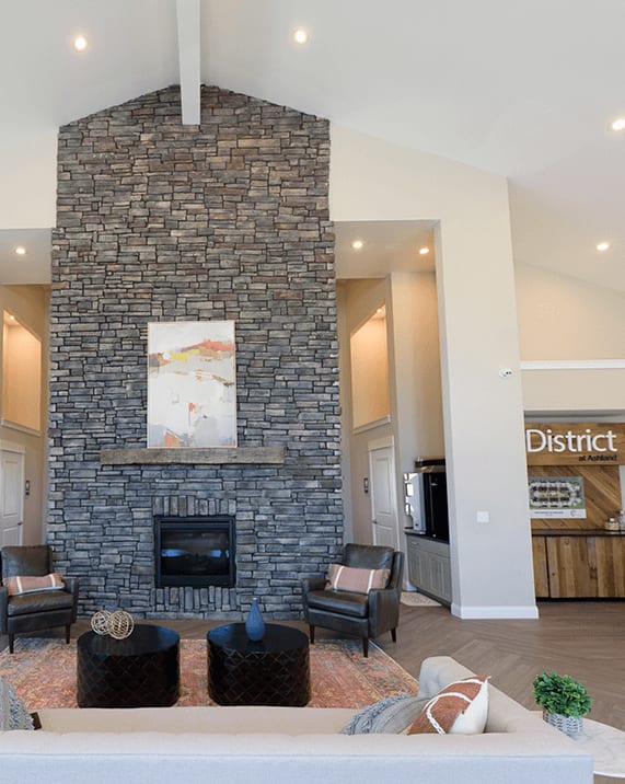 a living room with a fireplace and a kitchen in the background