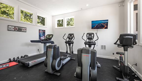 A room with a treadmill, elliptical trainer and a stationary bike.