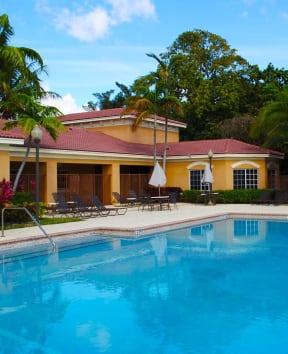 a large swimming pool in front of a yellow house with a blue pool at Renaissance, West Palm Beach