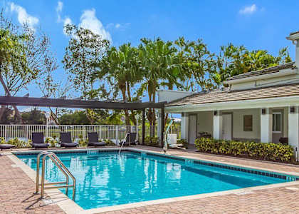 A swimming pool with a metal ladder and a house in the background.