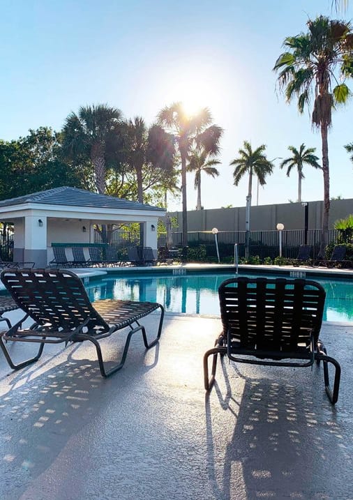 a swimming pool with chaise lounge chairs   and palm trees at Oaks at Pompano, Pompano Beach, 33060