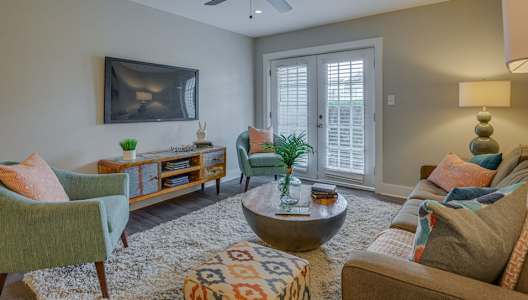 A living room with a ceiling fan, a couch, a chair, a coffee table, and a rug.