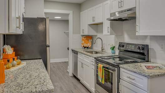 A kitchen with a granite counter top and stainless steel appliances.