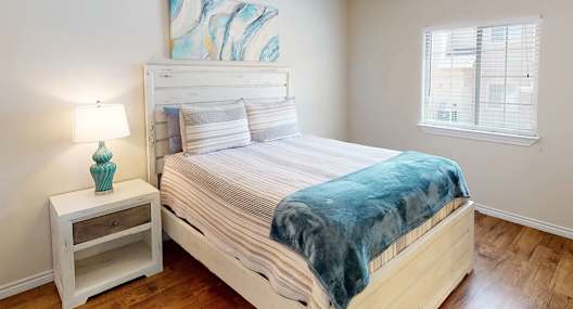 A bedroom with a bed, a nightstand, and a ceiling fan.