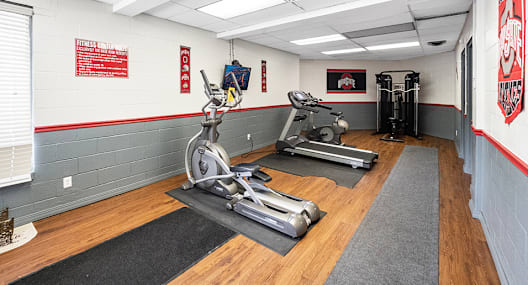 A gym with a row of treadmills and a row of stationary bikes.