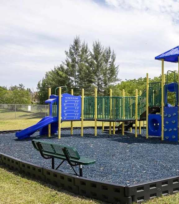 A playground with a green and yellow slide and a wooden structure.
