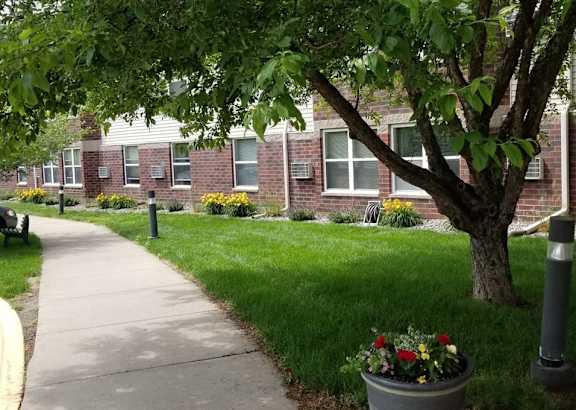 a sidewalk in front of a brick apartment building