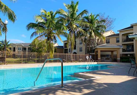 a swimming pool with palm trees in front of apartment buildings at Portofino, Palm Springs