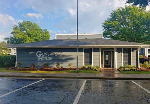 a building with a sign on the side of a parking lot  at Governors House, Huntsville, AL, 35805