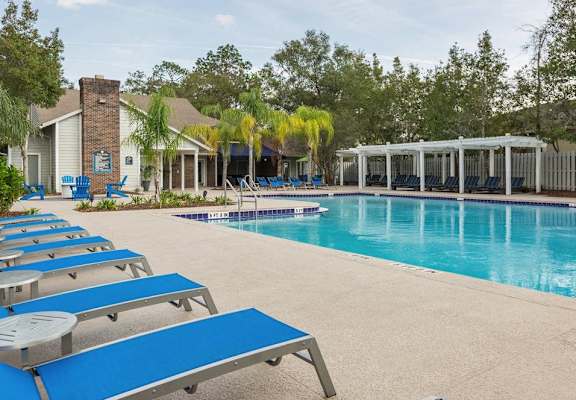 a large swimming pool with blue lounge chairs