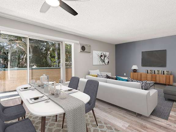Hardwood floored dining room with ceiling fan and view of living room and private balcony.