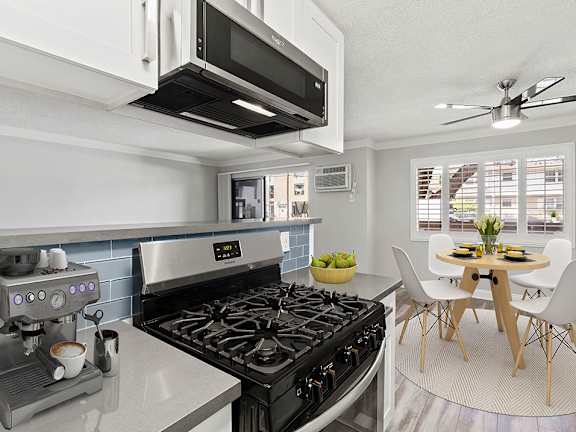 Blue tiled kitchen with stainless steel oven and microwave and view of hardwood floor dining room.