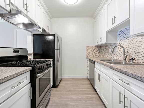Custom tiled kitchen with stainless steel fridge, sink, and oven.