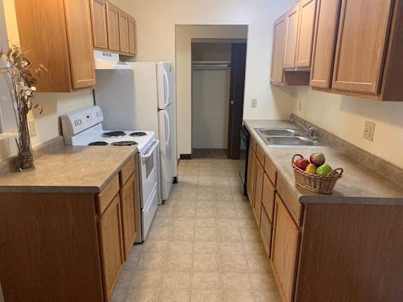 A kitchen with wooden cabinets and a white stove top oven.