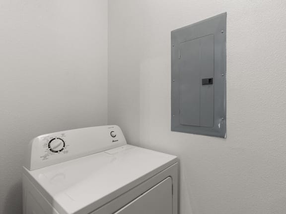 a white washer and dryer in a white room with a silver door