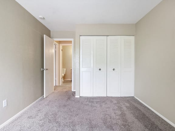a bedroom with closet doors and carpeting
