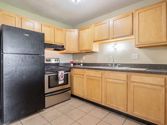a kitchen with wooden cabinets and a black refrigerator