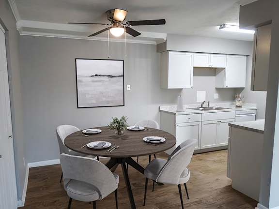 A dining room with a table set for two and a ceiling fan.