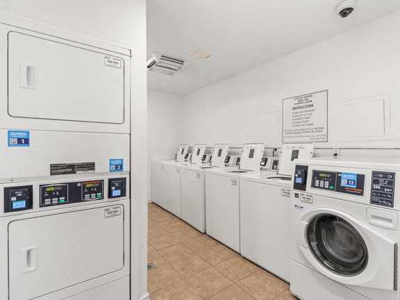 a row of washing machines and dryers in a laundry room