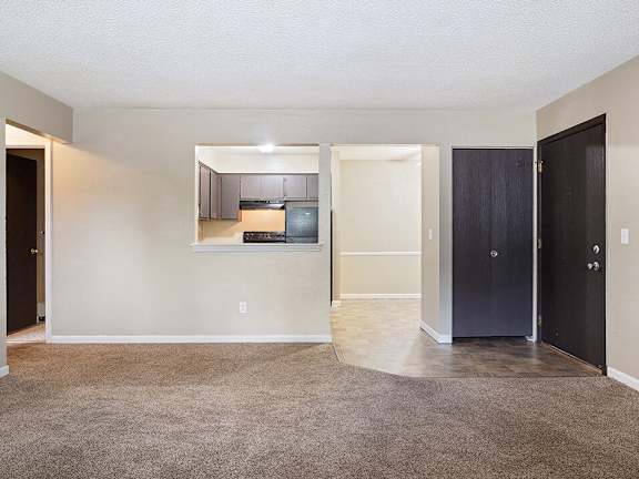 an empty living room and kitchen with a black door