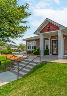 the front of a small house with a porch and a lawn