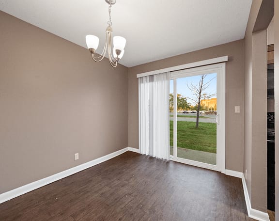 an empty living room with a sliding glass door to a yard