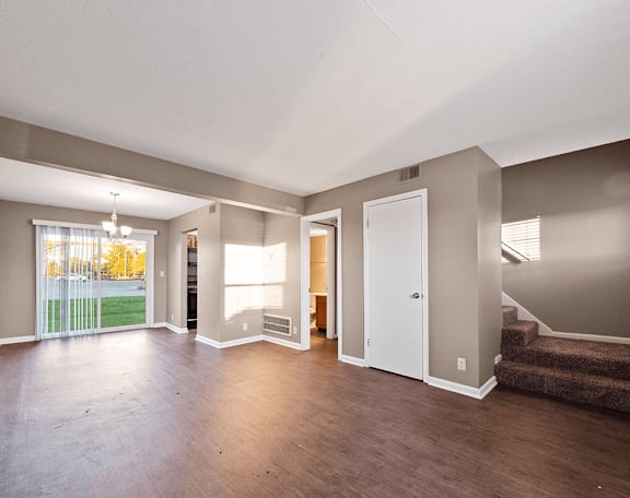 an empty living room with hard wood floors and a staircase