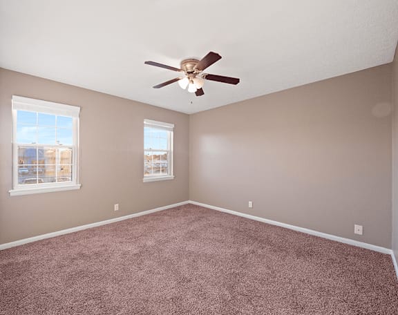 an empty room with carpet and a ceiling fan