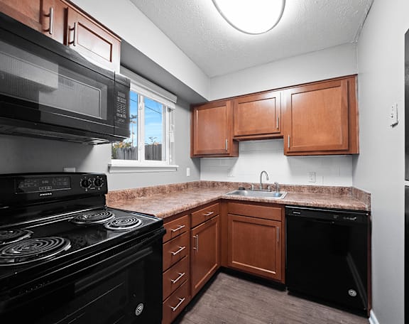 an empty kitchen with black appliances and a granite counter top